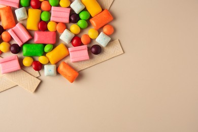 Photo of Many different chewing gums on beige background, flat lay. Space for text