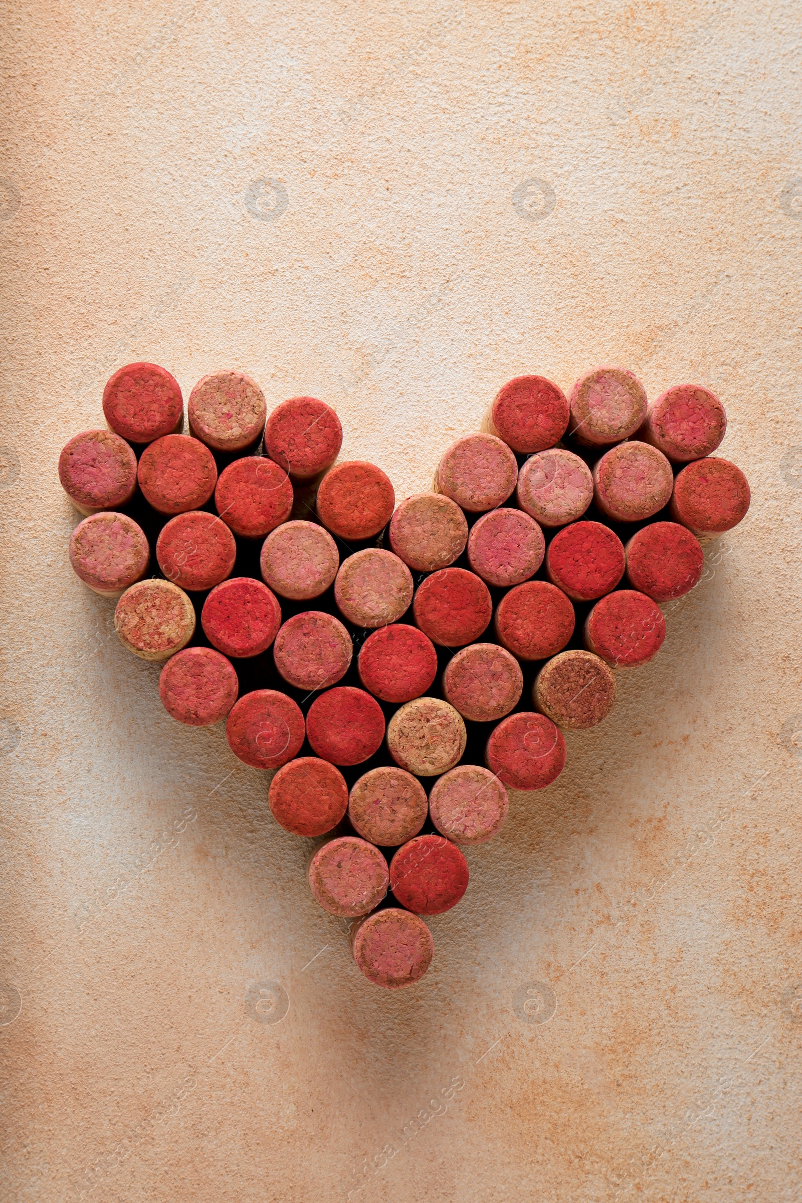 Photo of Heart made of wine bottle corks on textured table, top view