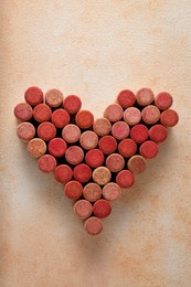 Photo of Heart made of wine bottle corks on textured table, top view