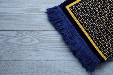 Photo of Muslim prayer rug on grey wooden table, top view. Space for text