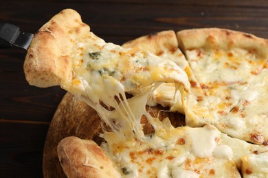 Photo of Taking piece of delicious cheese pizza at wooden table, closeup