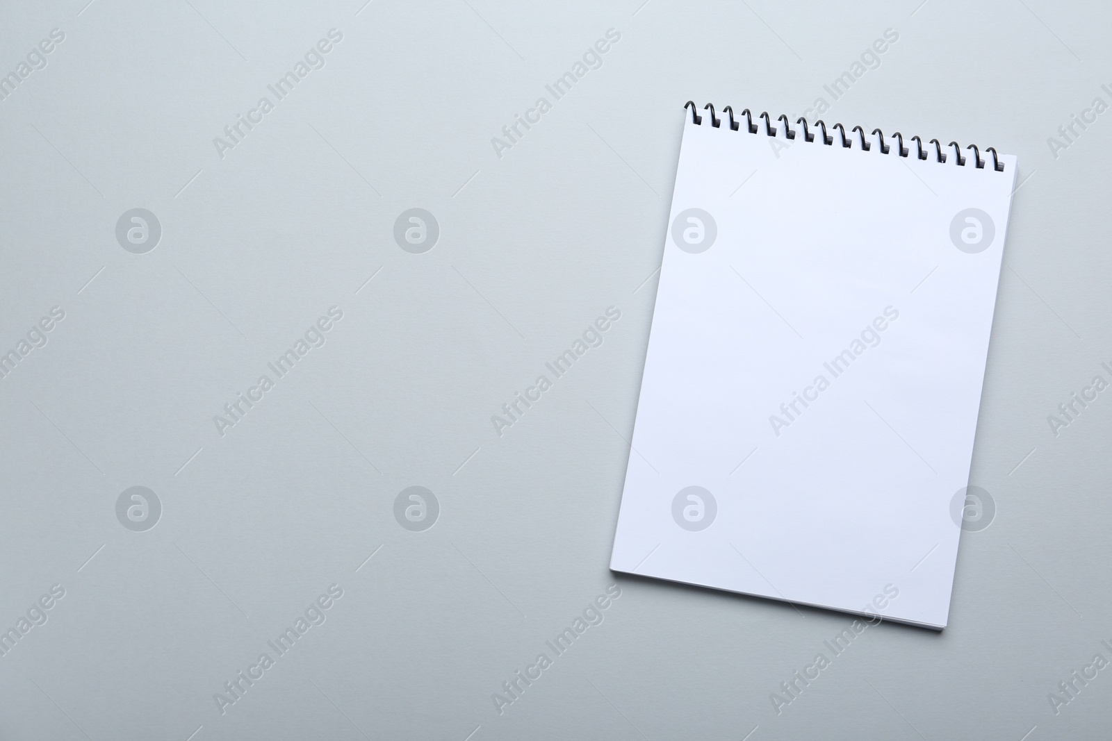 Photo of One notebook on light grey background, top view. Space for text