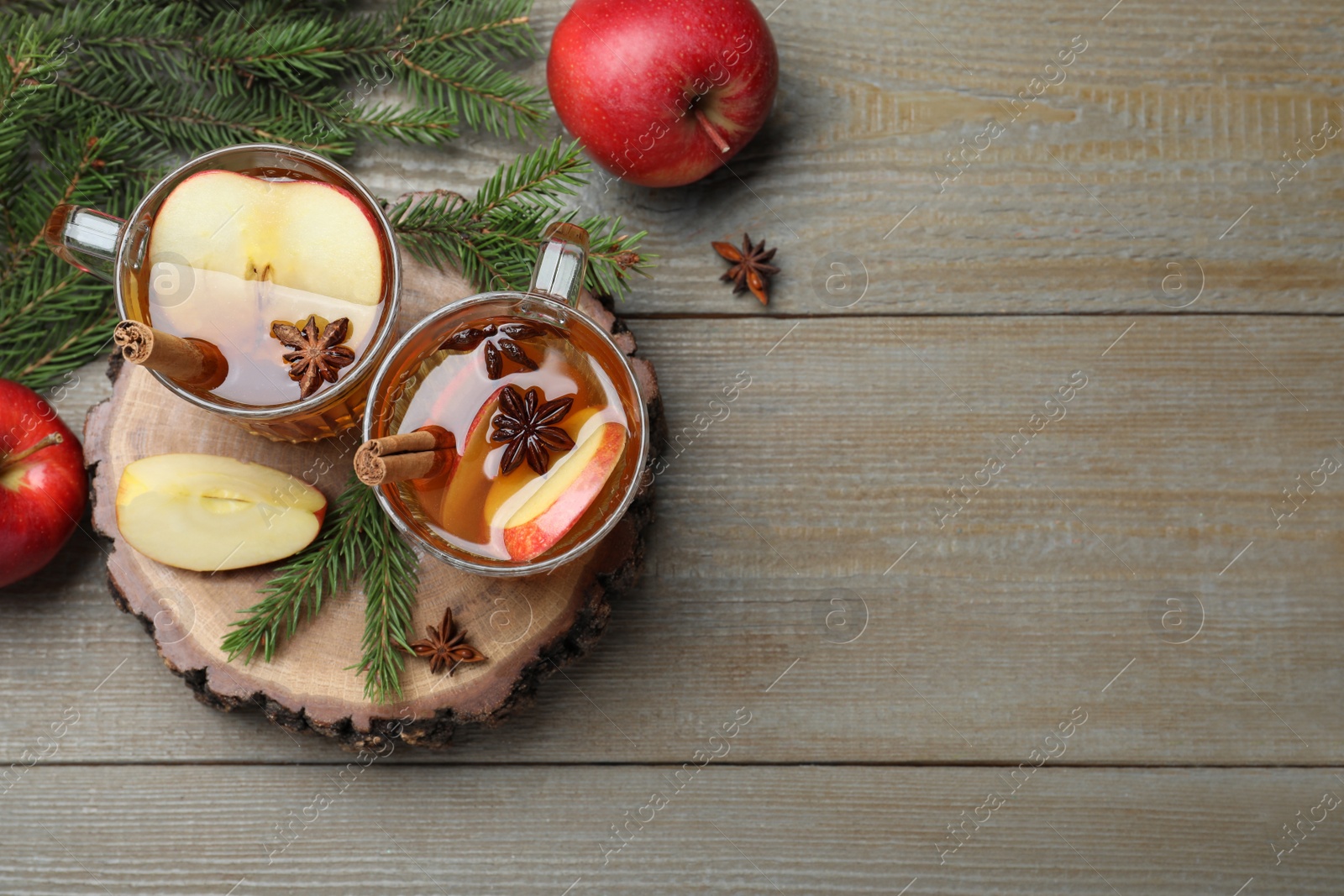 Photo of Hot mulled cider, fresh fruits and fir branches on wooden table, flat lay. Space for text