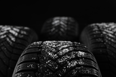Photo of Set of new winter tires on black background, closeup