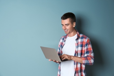 Man in casual clothes with laptop on color background