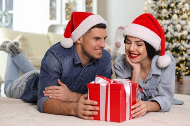 Happy couple with Christmas gift box at home