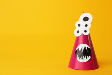 Photo of Funny pink monster on yellow background, space for text. Halloween decoration