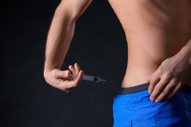 Photo of Man injecting himself on black background, closeup. Doping concept