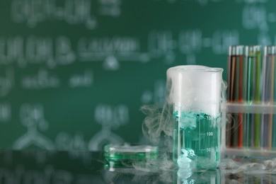 Laboratory glassware and test tubes with colorful liquids on glass table, space for text. Chemical reaction