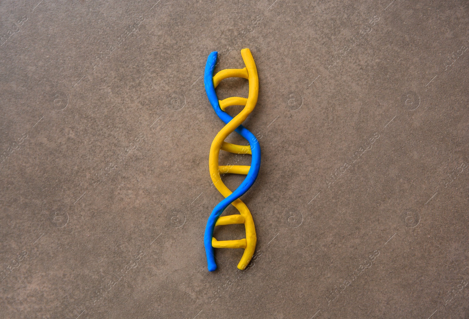 Photo of DNA molecule model made of colorful plasticine on brown background, top view