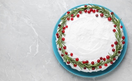 Traditional Christmas cake decorated with rosemary and cranberries on light grey marble table, top view. Space for text