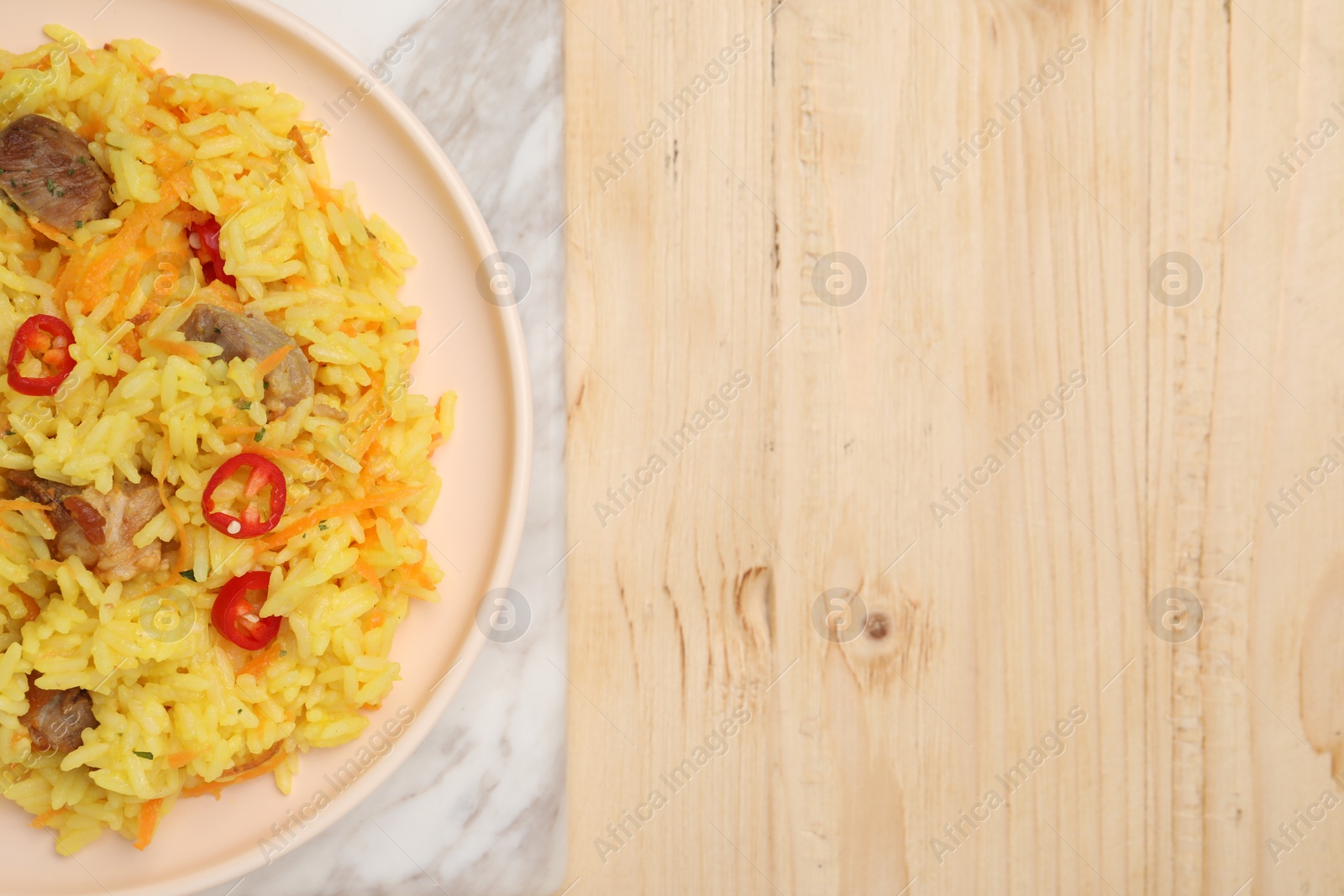 Photo of Delicious pilaf with meat on wooden table, top view. Space for text