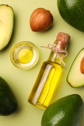 Photo of Cooking oil and fresh avocados on light green background, flat lay