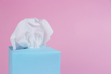 Box with paper tissues on pink background, closeup. Space for text