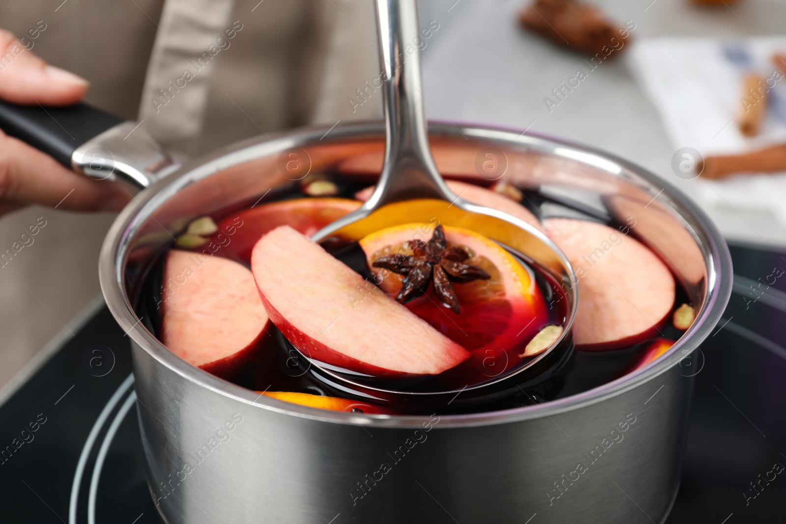 Photo of Woman cooking delicious mulled wine at stove, closeup