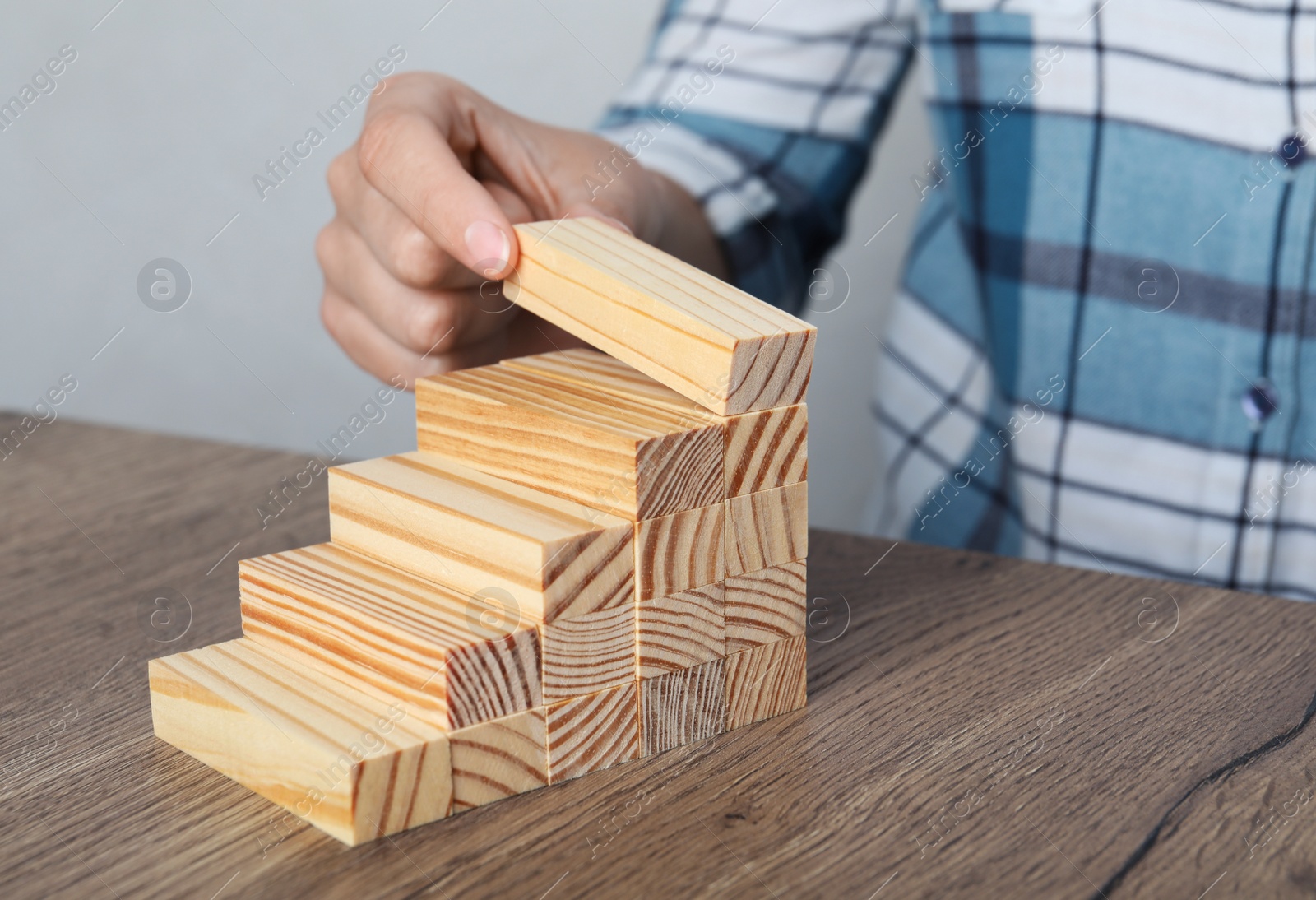 Photo of Woman building steps with wooden blocks at table, closeup. Career ladder