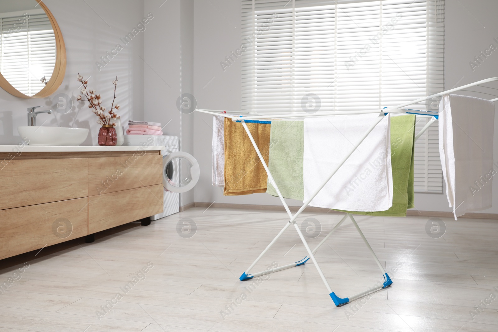 Photo of Clean terry towels hanging on drying rack at home