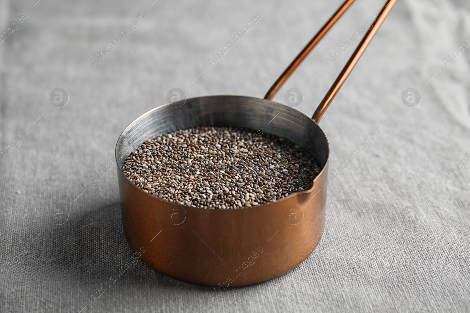 Photo of Saucepan with chia seeds on grey fabric