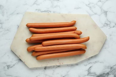 Photo of Fresh delicious sausages on white marble table, top view