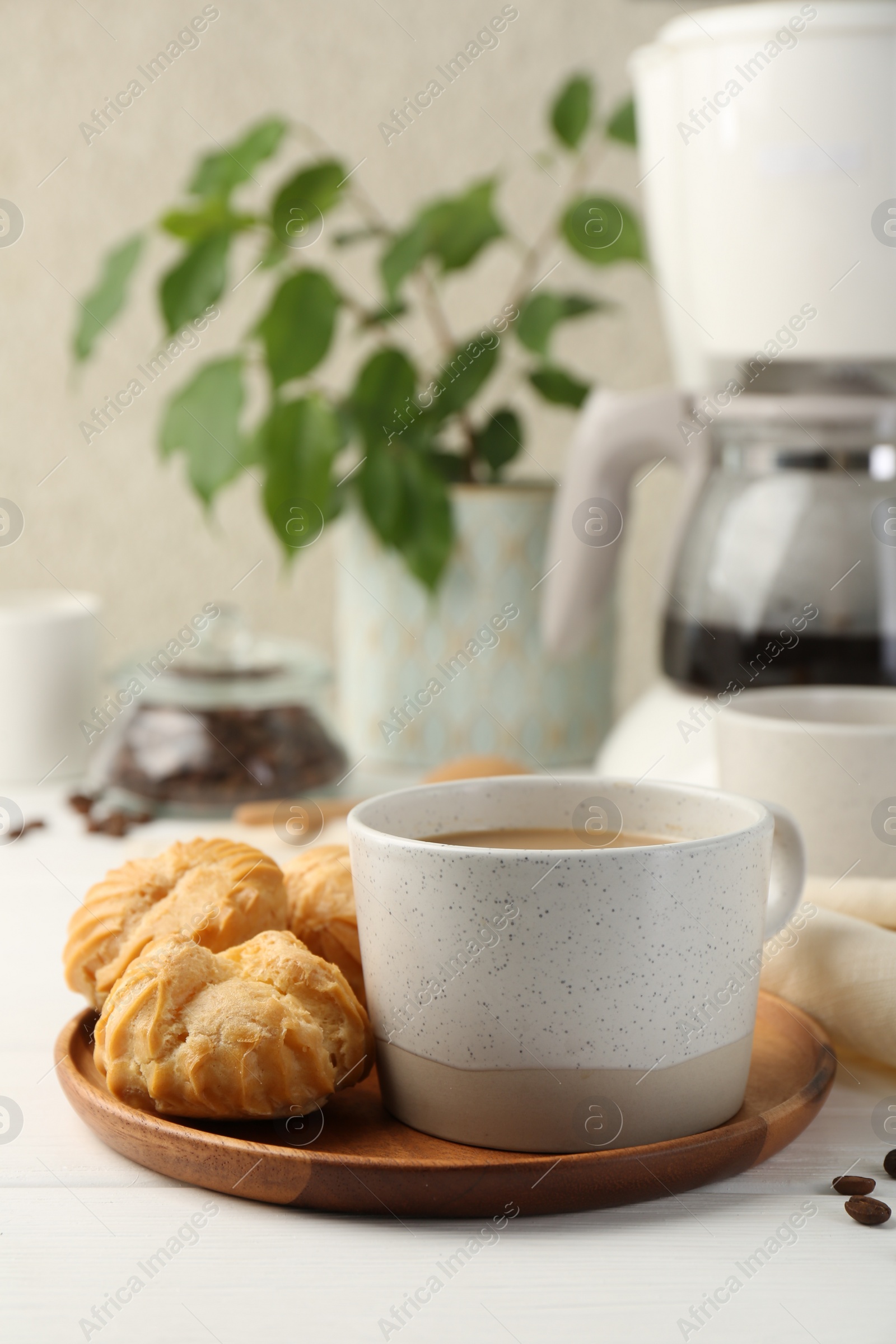 Photo of Aromatic coffee in cup and tasty profiteroles on white wooden table