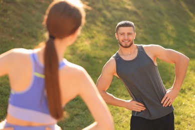 Attractive couple doing sports exercises in park on sunny day. Stretching outdoors