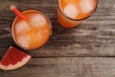 Tasty freshly made grapefruit juice and fruit on wooden table, top view. Space for text