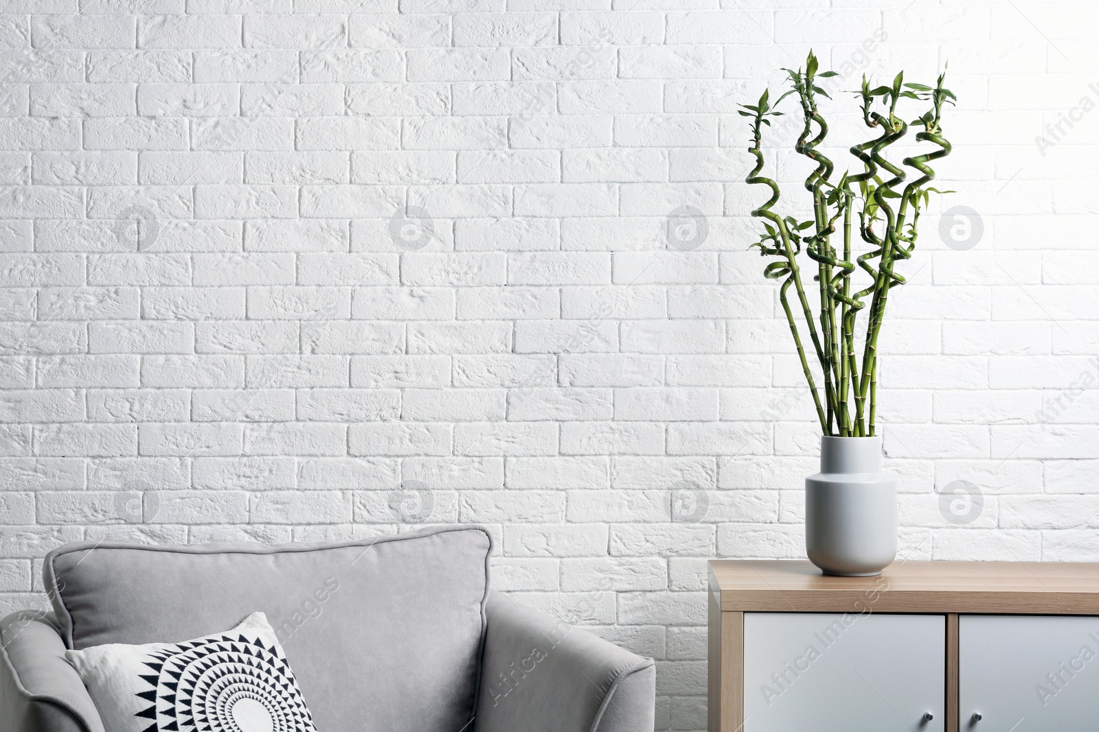 Photo of Vase with green bamboo on table in living room. Space for text