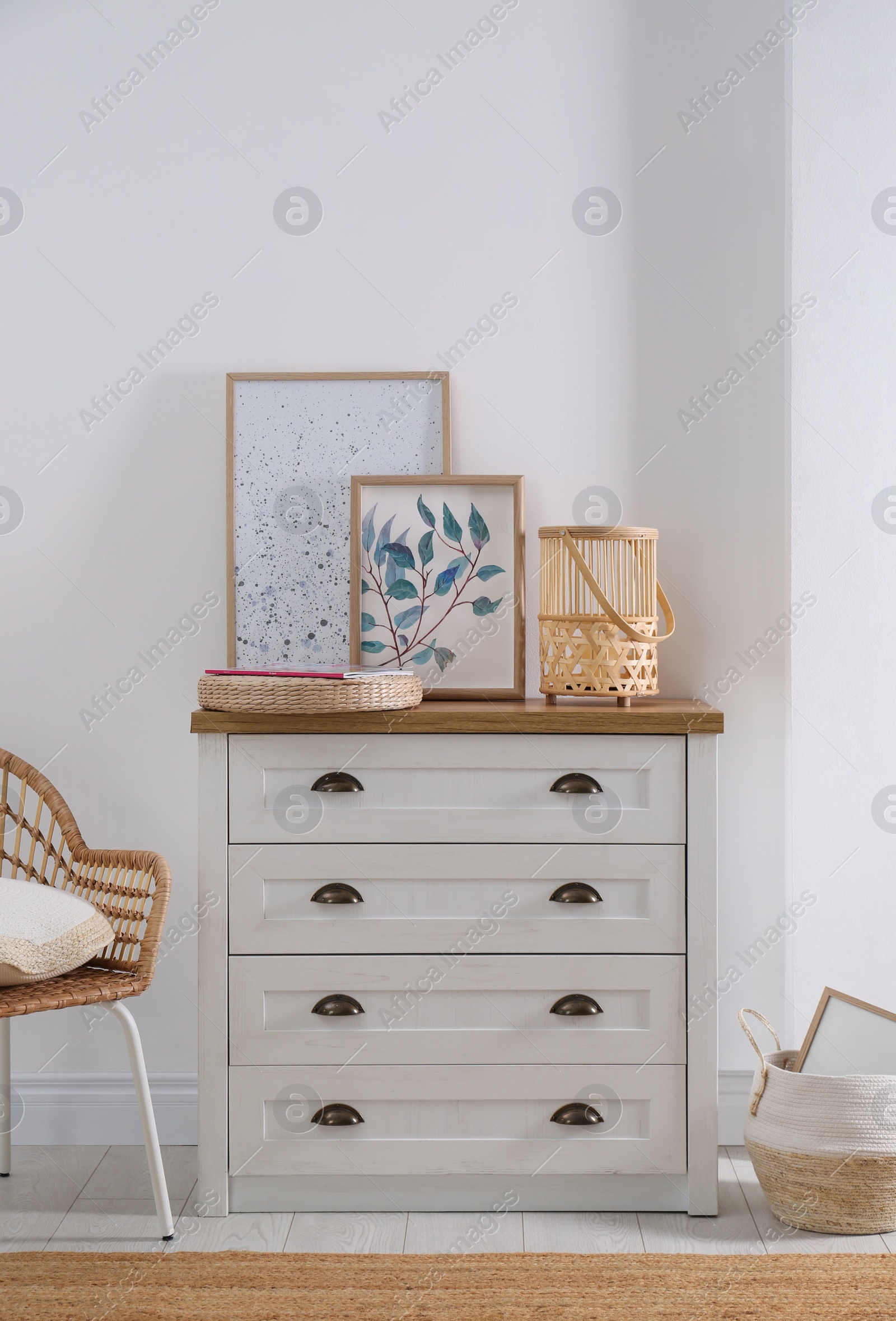 Photo of Stylish wicker holder with candle on chest of drawers indoors