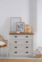 Photo of Stylish wicker holder with candle on chest of drawers indoors