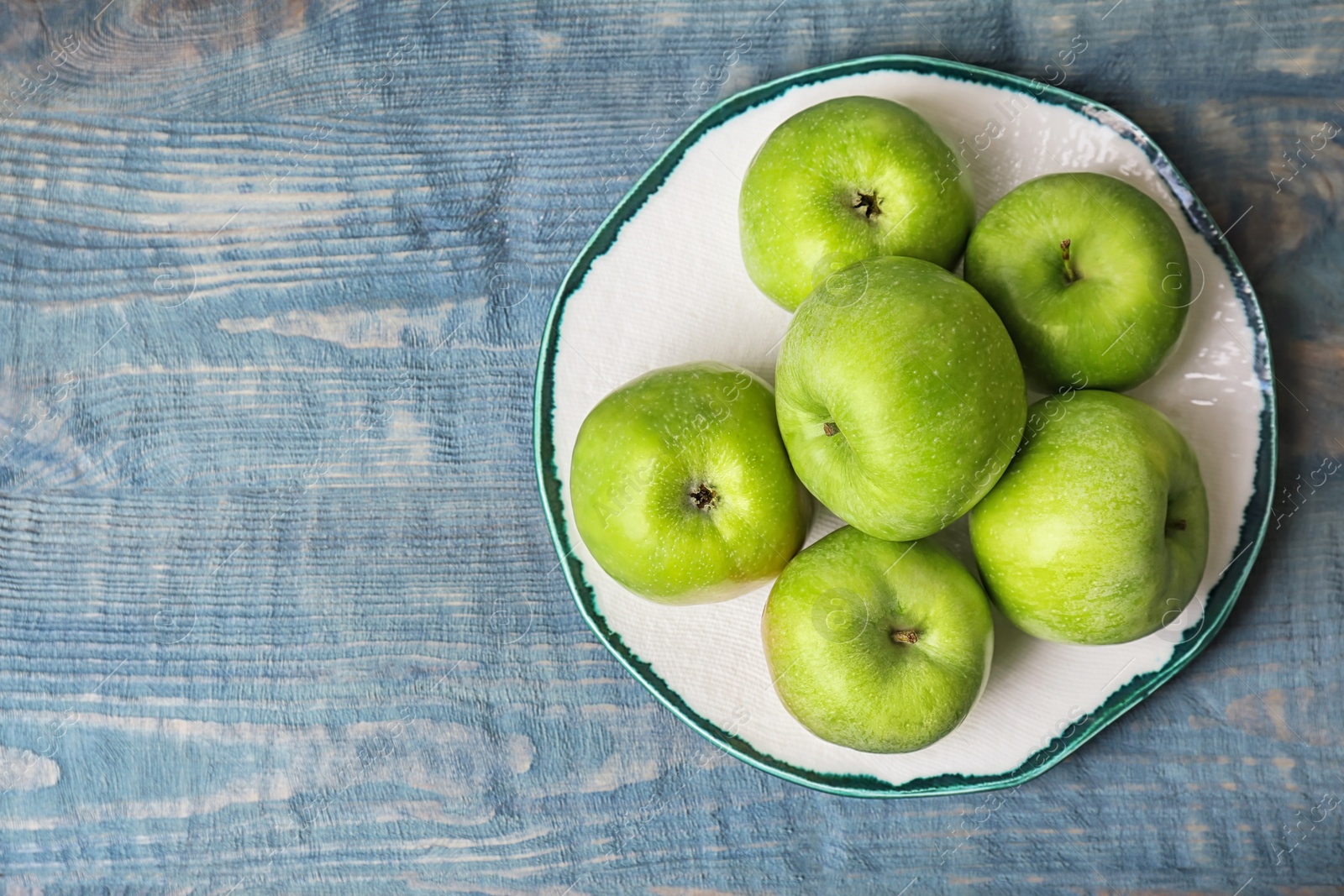 Photo of Plate with fresh green apples on wooden background, top view