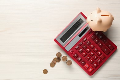 Calculator, coins and piggy bank on white wooden table, flat lay. Space for text