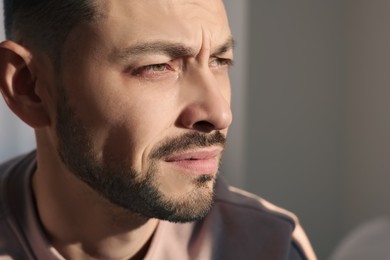 Upset man crying indoors, closeup. Loneliness concept