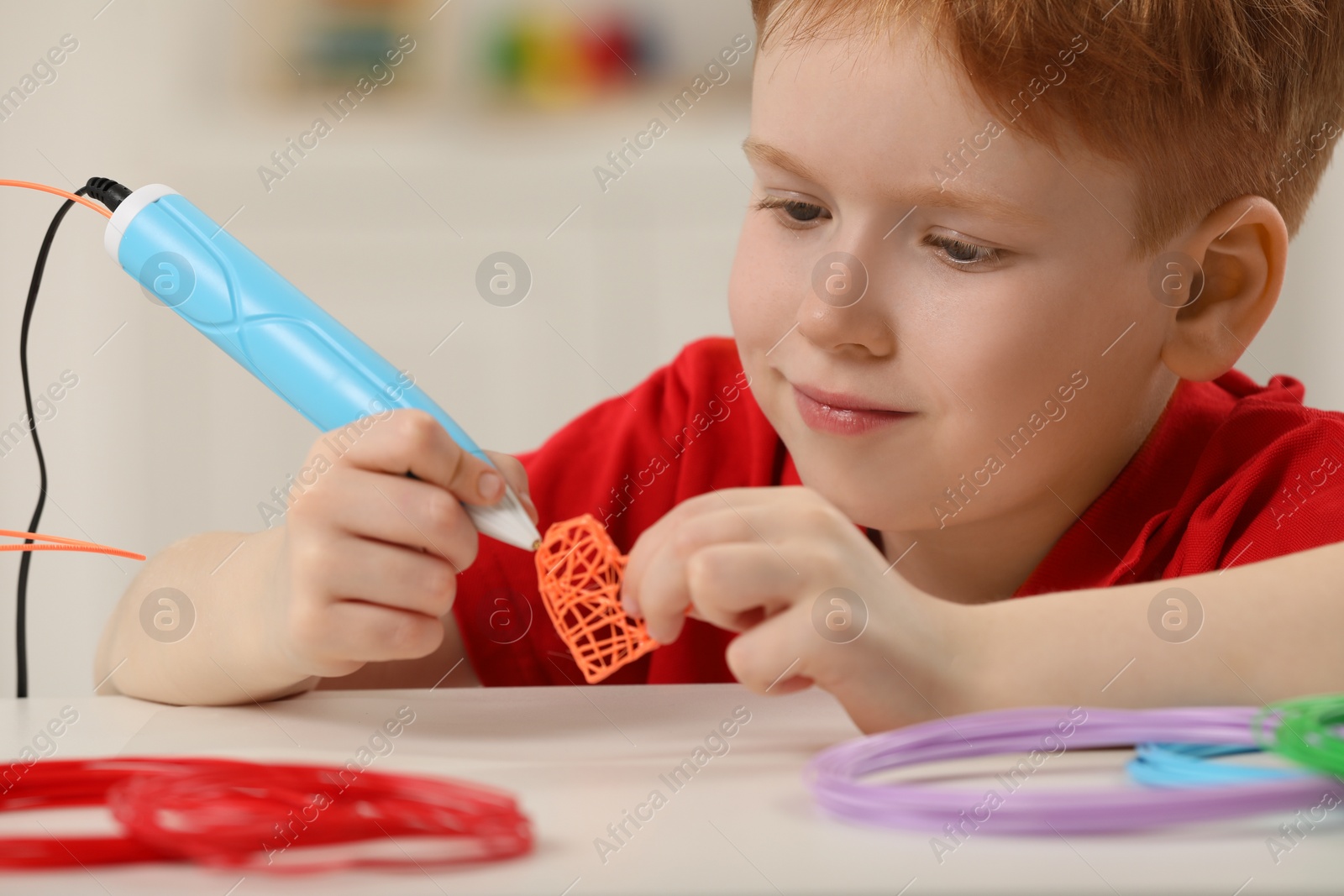 Photo of Boy drawing with stylish 3D pen at white table