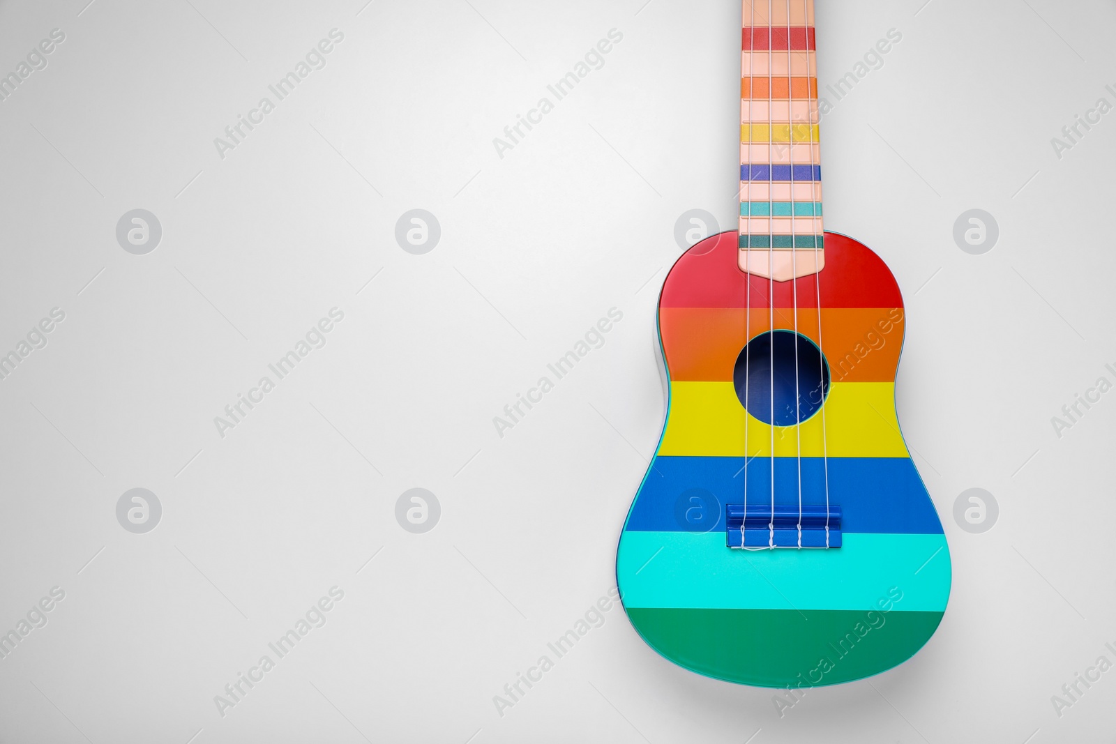 Photo of Colorful ukulele on white background, top view and space for text. String musical instrument