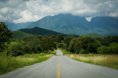 Photo of Picturesque view of empty road near trees and mountains