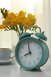 Photo of Alarm clock on white table indoors. Morning time