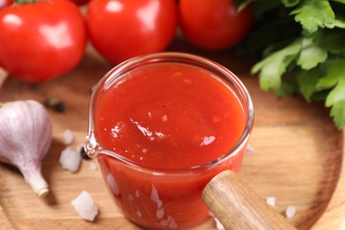 Photo of Delicious ketchup on wooden plate, closeup. Tomato sauce