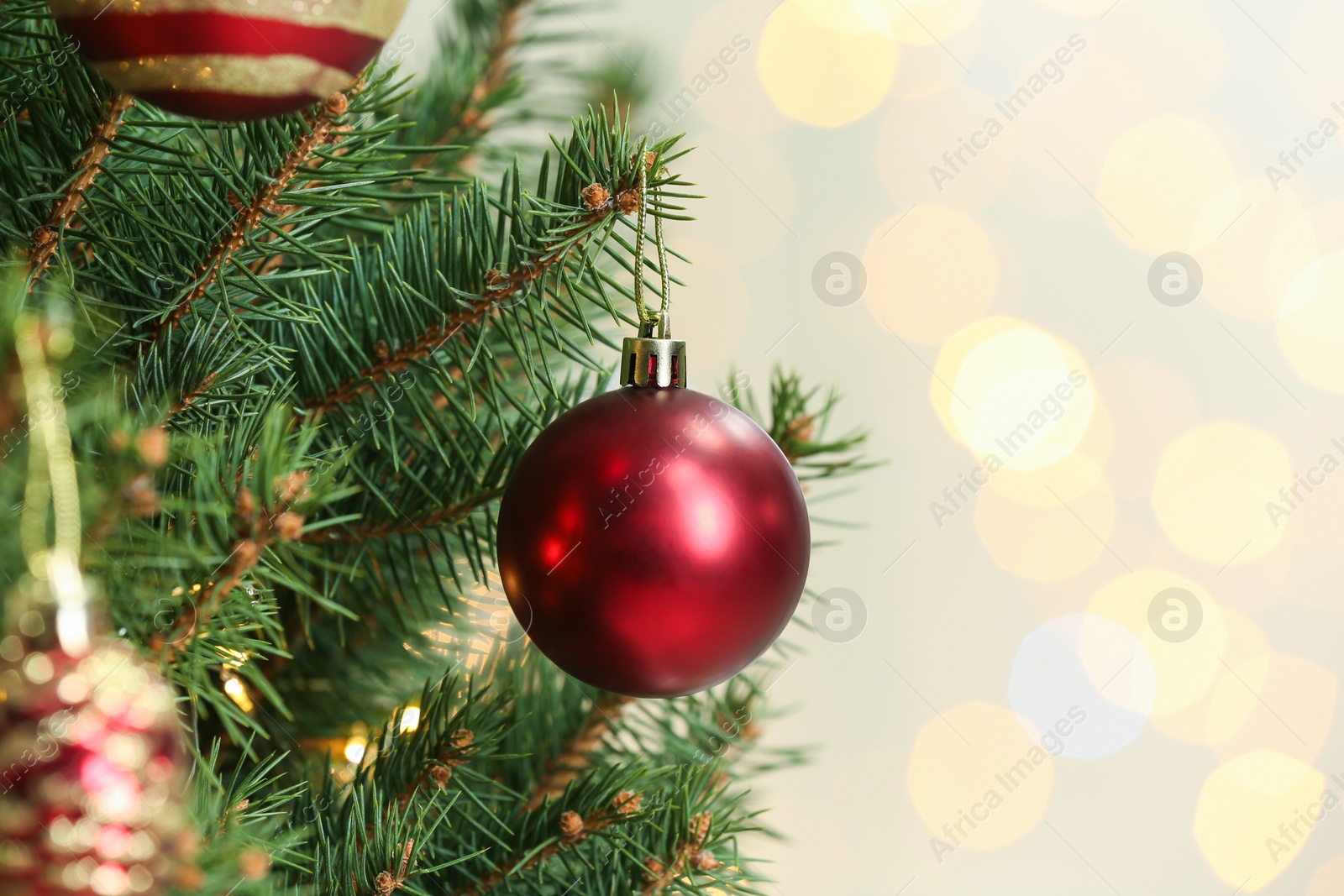 Photo of Red holiday bauble hanging on Christmas tree against blurred lights, closeup