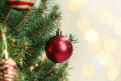 Photo of Red holiday bauble hanging on Christmas tree against blurred lights, closeup