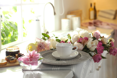 Photo of Beautiful peonies and breakfast on kitchen counter