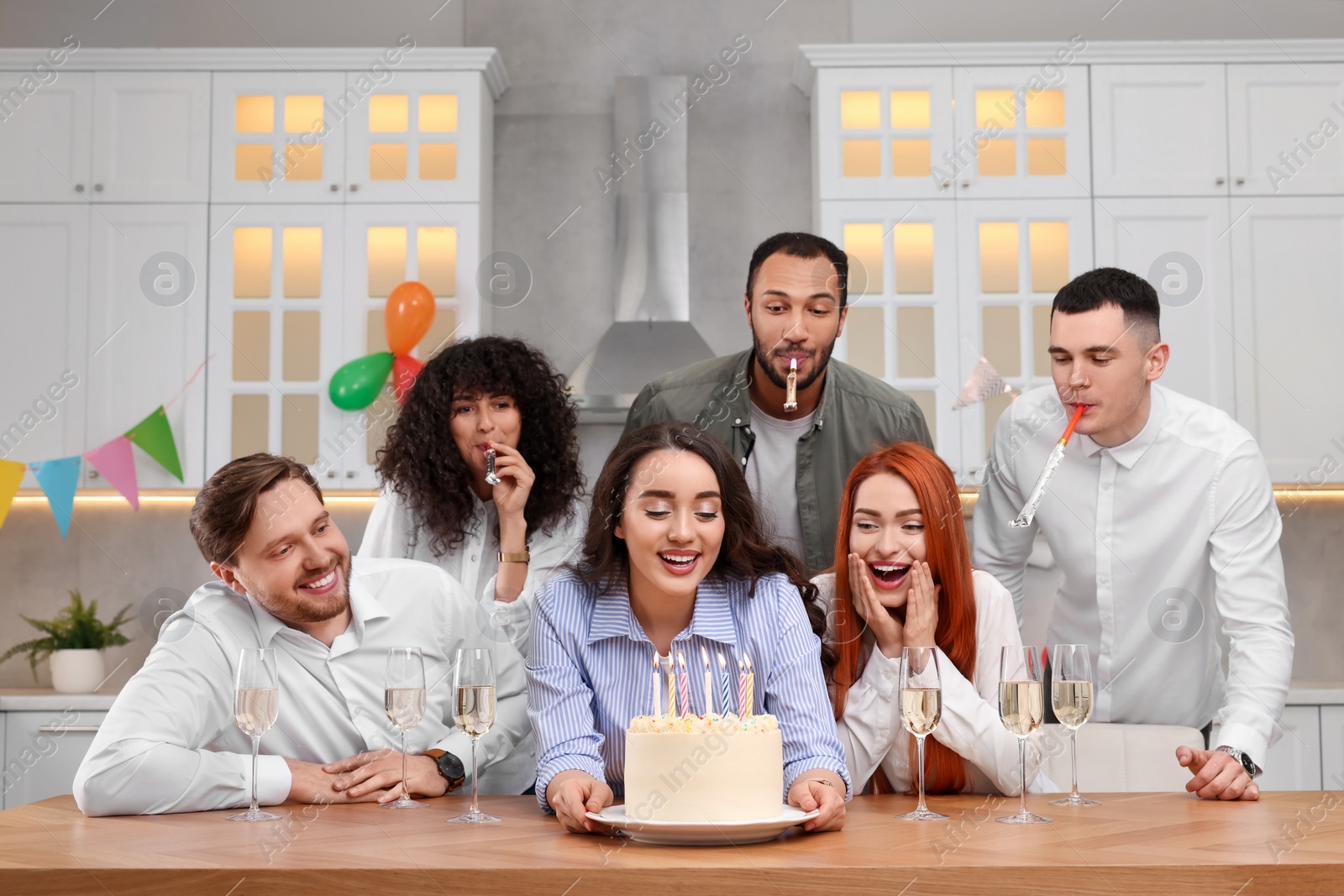 Photo of Happy friends with tasty cake celebrating birthday in kitchen