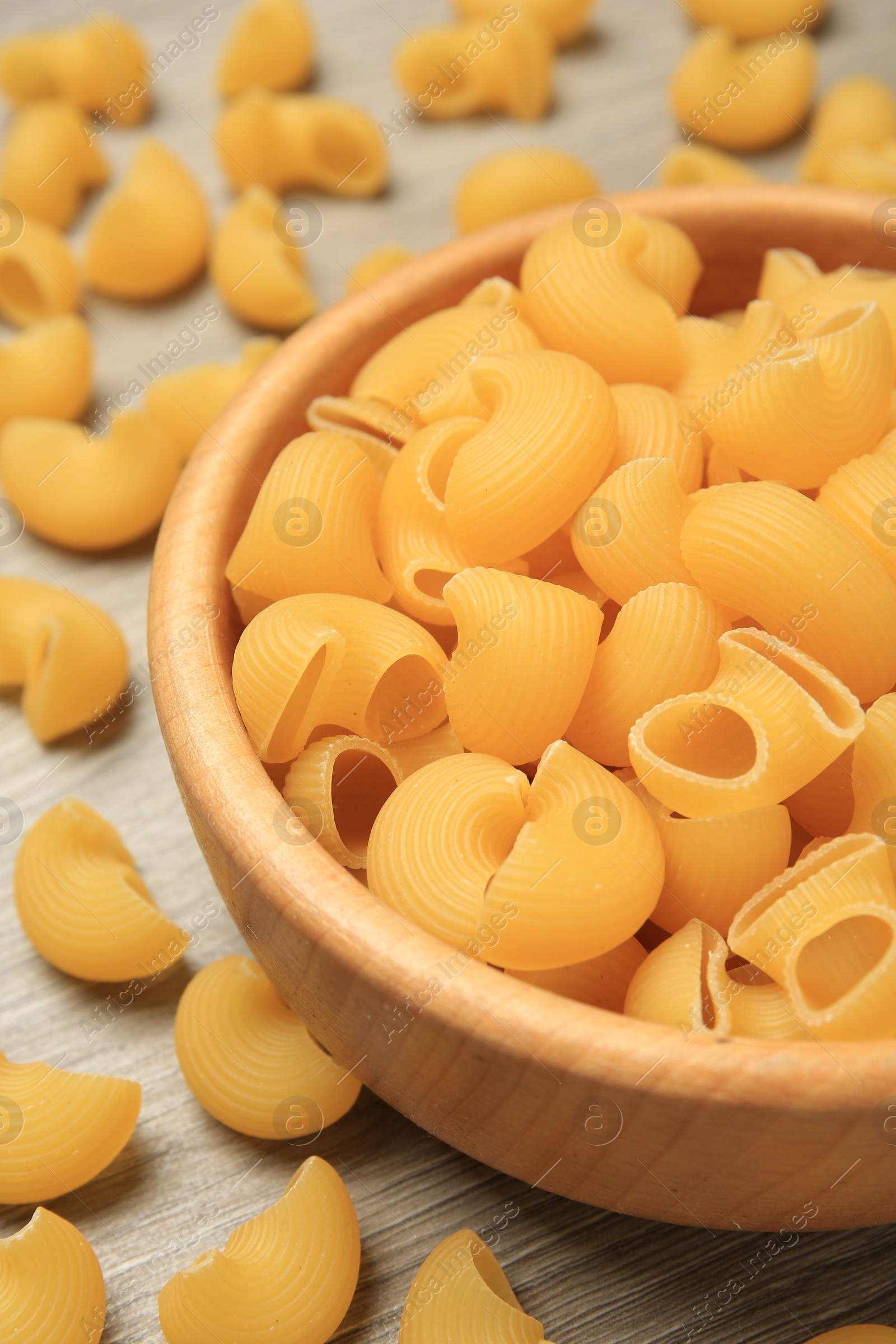 Photo of Raw macaroni pasta on wooden table, closeup