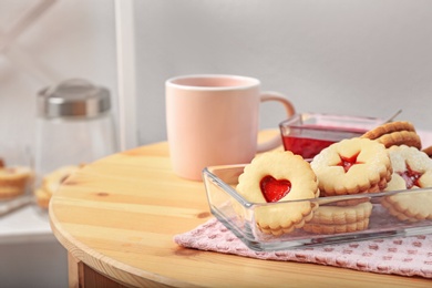 Photo of Traditional Christmas Linzer cookies with sweet jam and cup of tea on table