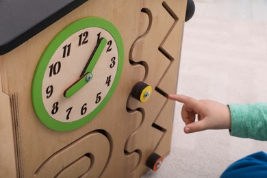 Little child playing with busy board house on floor, closeup