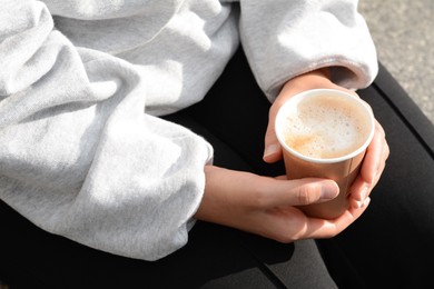 Woman sitting with cardboard cup of coffee, closeup