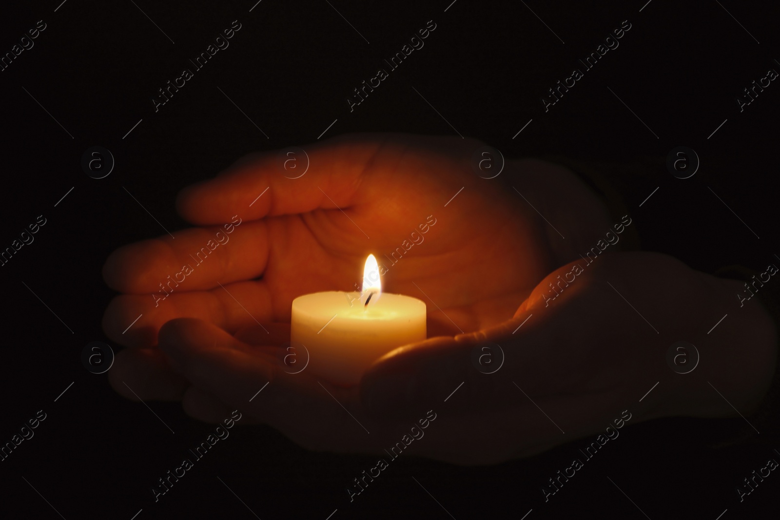 Photo of Young person holding burning candle in darkness, closeup