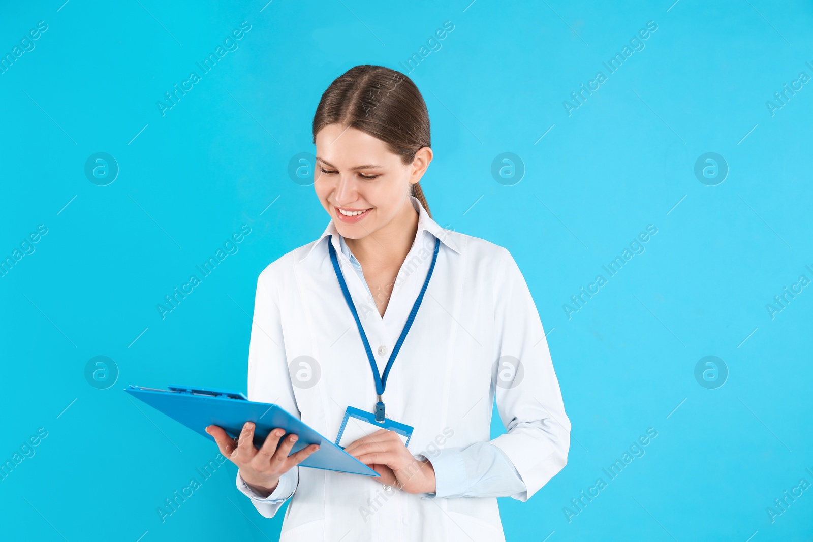Photo of Young doctor with clipboard on blue background. Medical service