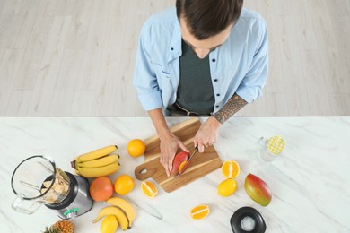 Photo of Man preparing ingredients for tasty smoothie at white marble table, above view