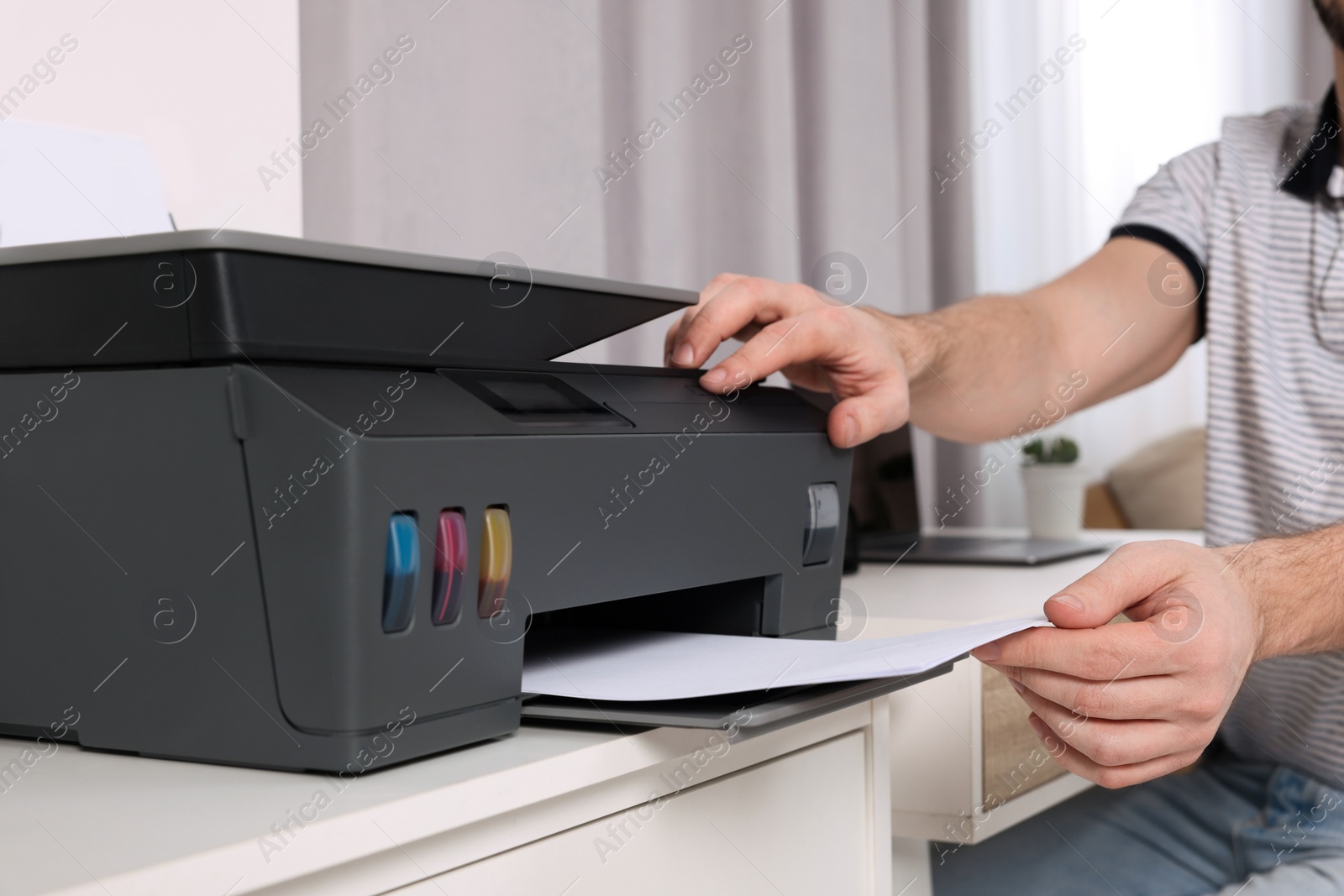 Photo of Man using modern printer at workplace indoors, closeup