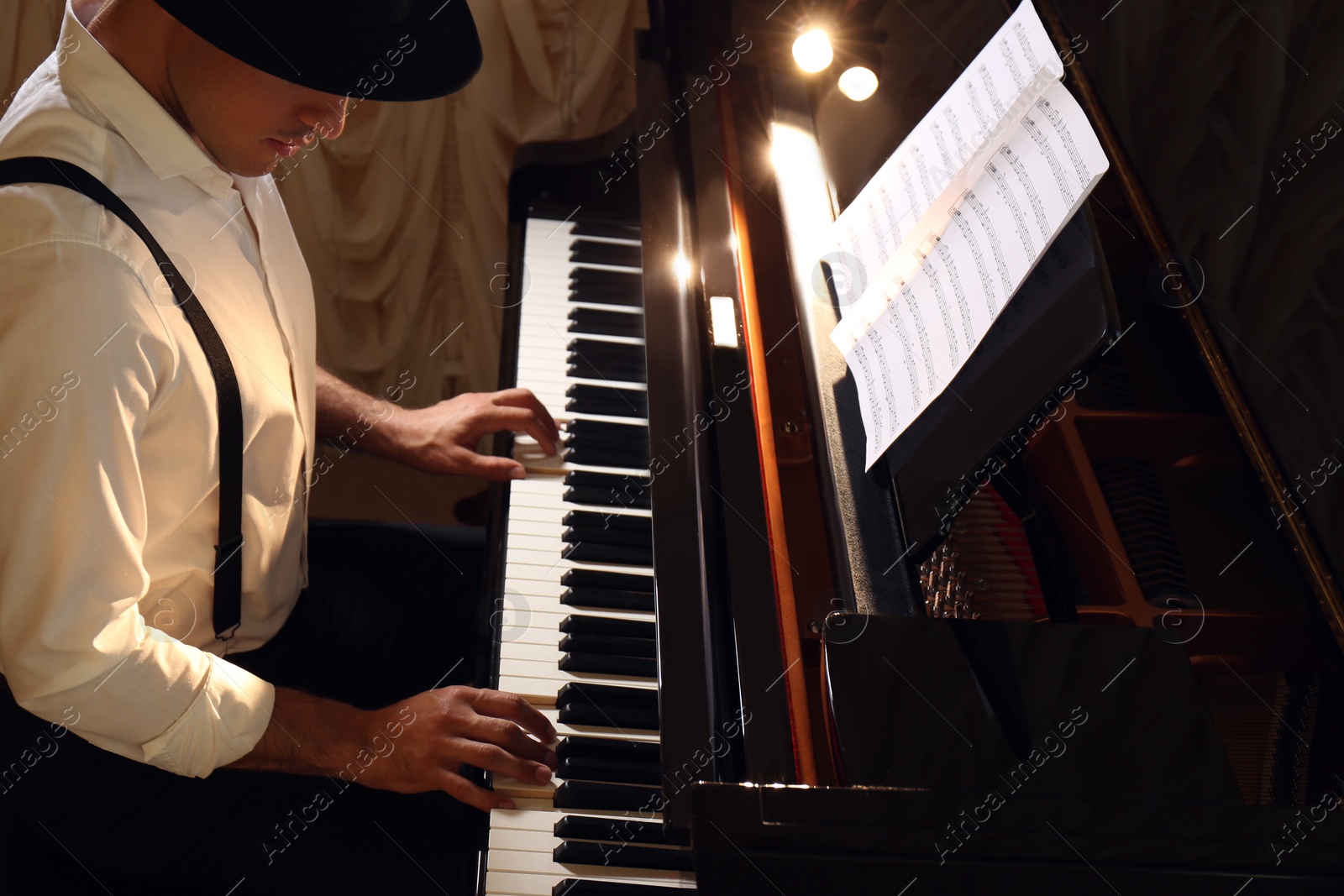 Photo of Man playing grand piano indoors. Talented musician